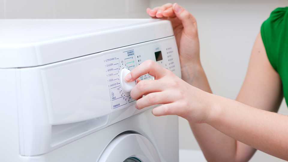 En person ställer in en tvättmaskin.