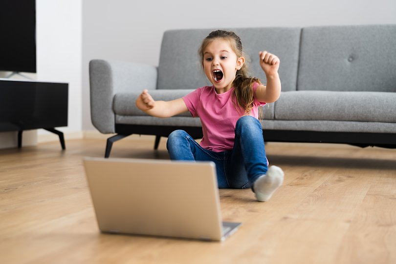 Ett glatt barn som sitter framför en dator.